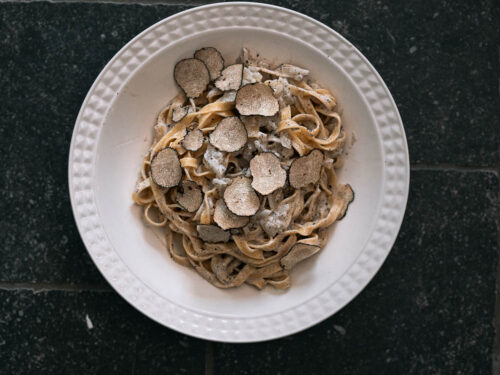 Bord met pasta met romige truffelsaus en schilfers zwarte truffel