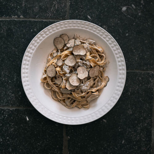 Bord met pasta met romige truffelsaus en schilfers zwarte truffel