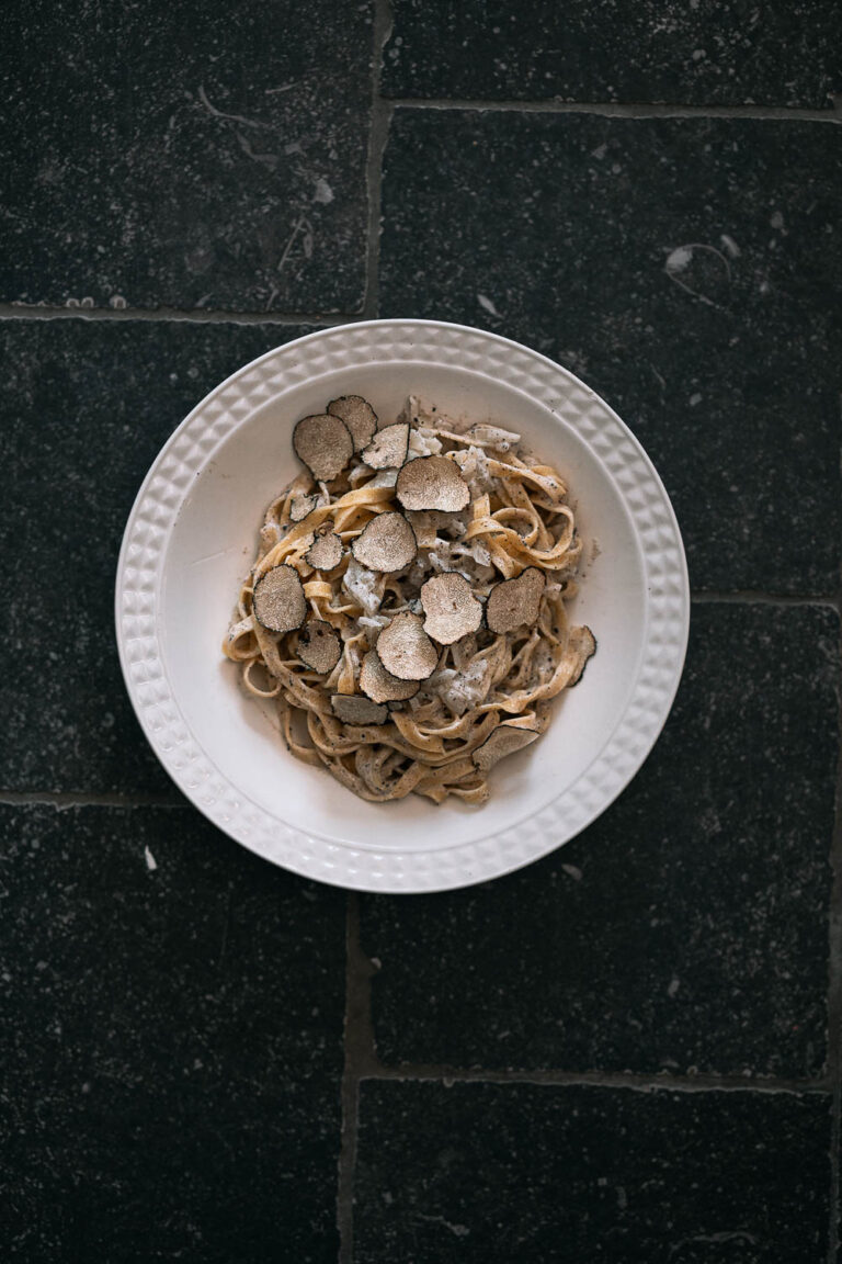 Bord met pasta met romige truffelsaus en schilfers zwarte truffel
