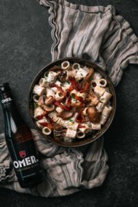 Pasta rigatoni met guanciale en een flesje OMER. bier er naast