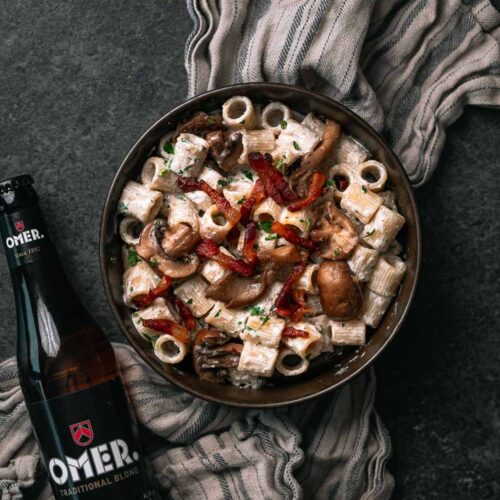 Pasta rigatoni met guanciale en een flesje OMER. bier er naast