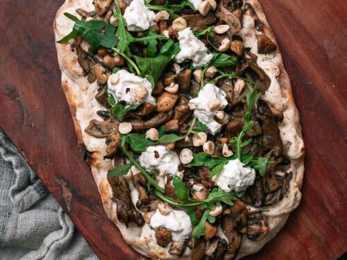 Herfstige Pinsa met champignons en truffel op ene houten plaat met een stoffen doekje eronder