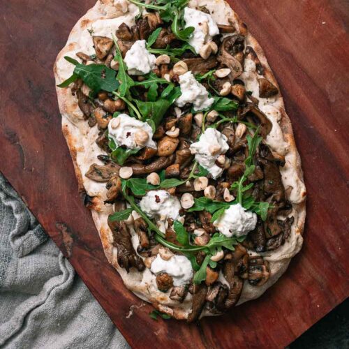 Herfstige Pinsa met champignons en truffel op ene houten plaat met een stoffen doekje eronder