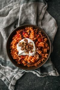 Pasta in tomatensaus met pancetta, burrata en pistachecrumble