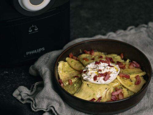 Verse pasta met pistachepesto, burrata en pancetta naast een Philips Pastamaker