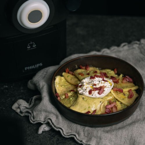 Verse pasta met pistachepesto, burrata en pancetta naast een Philips Pastamaker