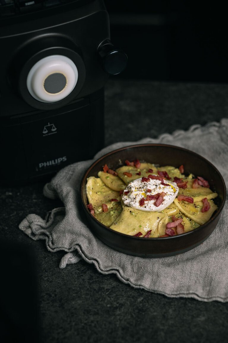 Verse pasta met pistachepesto, burrata en pancetta naast een Philips Pastamaker