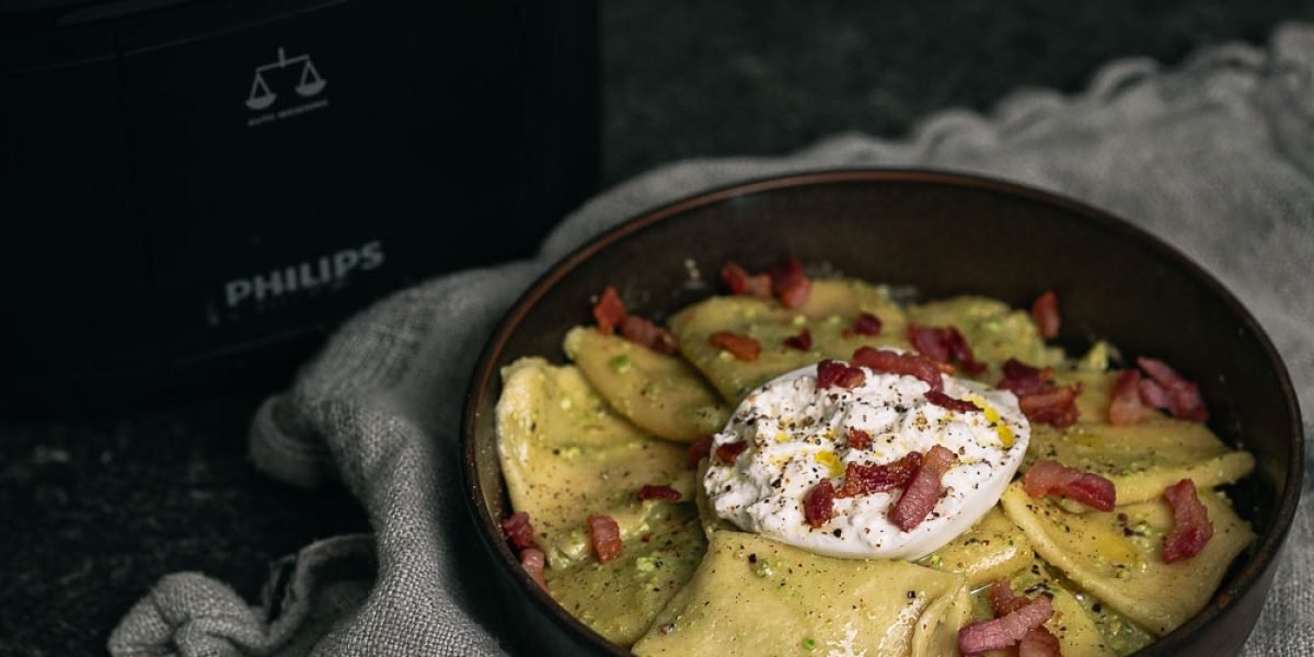 Verse pasta met pistachepesto, burrata en pancetta naast een Philips Pastamaker